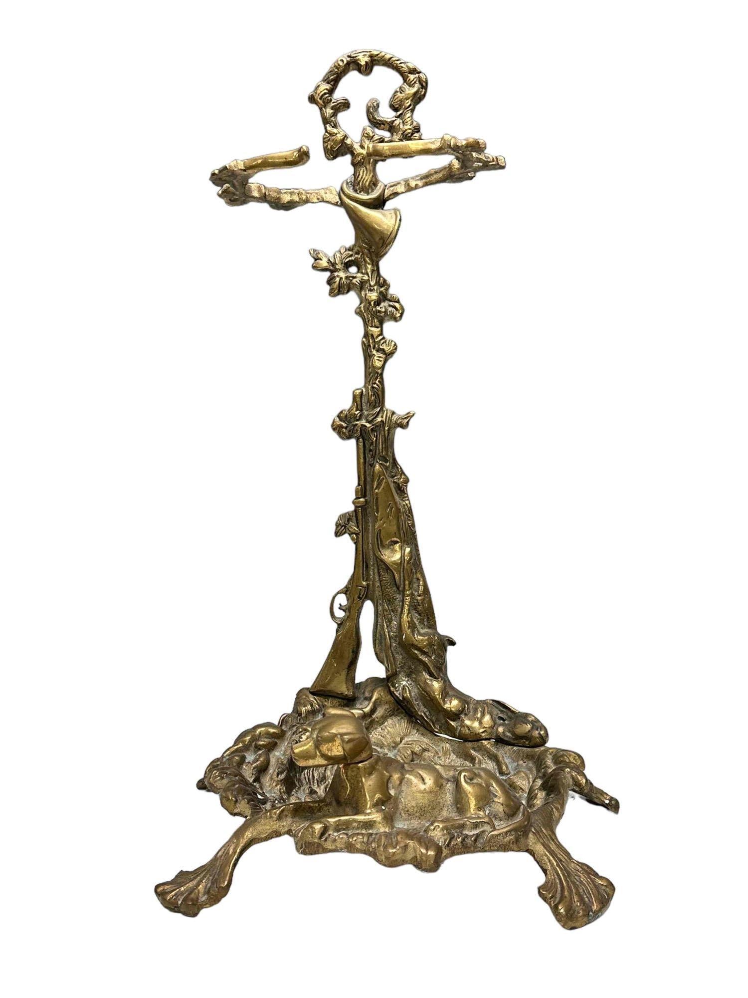 French Brass Hunting Dog Fireplace Tool Set: Ornate brass fireplace tool set that depicts a full figured dog that is laying on the front of the tray base. Note all the engraved floral details throughout this stand along with a rifle and hunting 