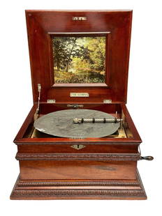 The Olympia 11 - 5/8" Disc Music Box: Olympia Mahogany 11 5/8 in. Disc Music Box. Orantely carved mahogany case on turned feet with carved border, signed with tag under the lid which reads The Olympia" ; single comb on an iron bed plate w