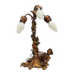 French Art Deco Cold Painted Figural Light: A wonderful and whimsical early 20th century gilt bronze cold painted lamp with three arched floral leaf lights. Depicting a young boy laying on leaf base with birds and a squirrel perched above eatin