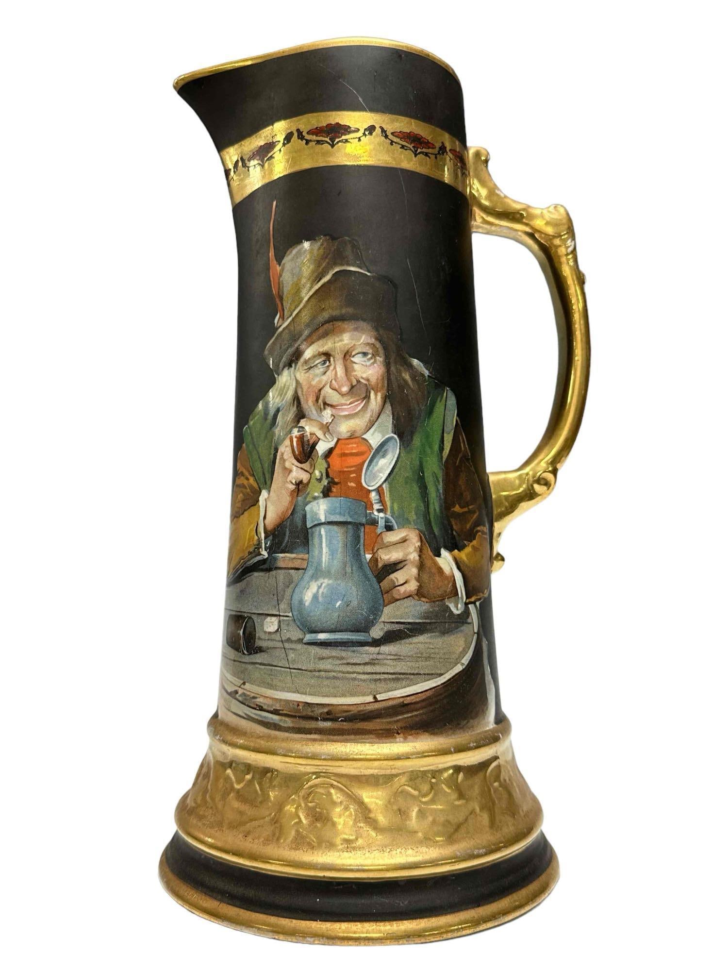 Egyptian Ware Art Tankard 12.5" tall: Transfer design on man drinking with painted mat black finish and gold decoration. Measures approx. 12'' high x 5 7/8'' base diameter. In age appropriate condition, see photos.