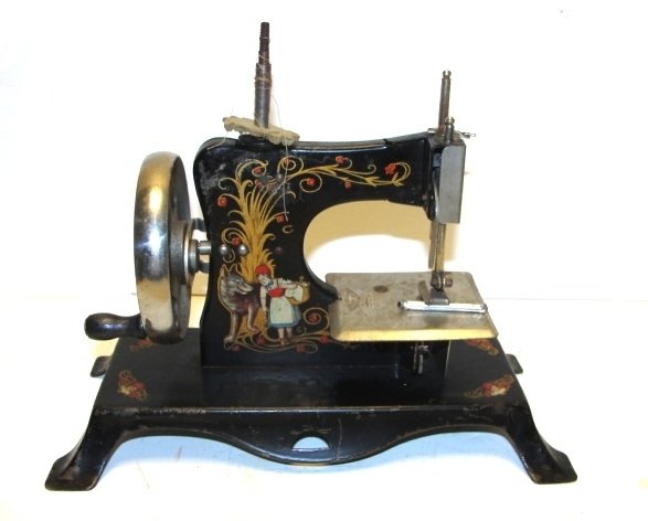 Little Red Riding Hood Child Sewing Machine: Stenciled with Little Red Riding Hood and the Wolf this old black toy sewing machine has a spread eagle with a key and made in Germany on the sewing platform. It is in very good condition for its age 
