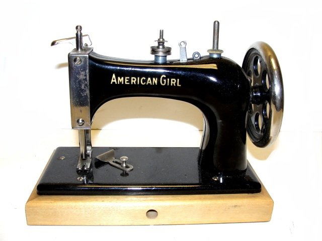 American Girl Vintage Childs Sewing Machine: Black enamel paint. Hinged to a wooden base ( 7 3/4" x 4") that will tilt backward to reveal a chain mechanism, and manufactures name. Black enamel paint. Hinged to a wooden base ( 7 3/4" x 4") that w
