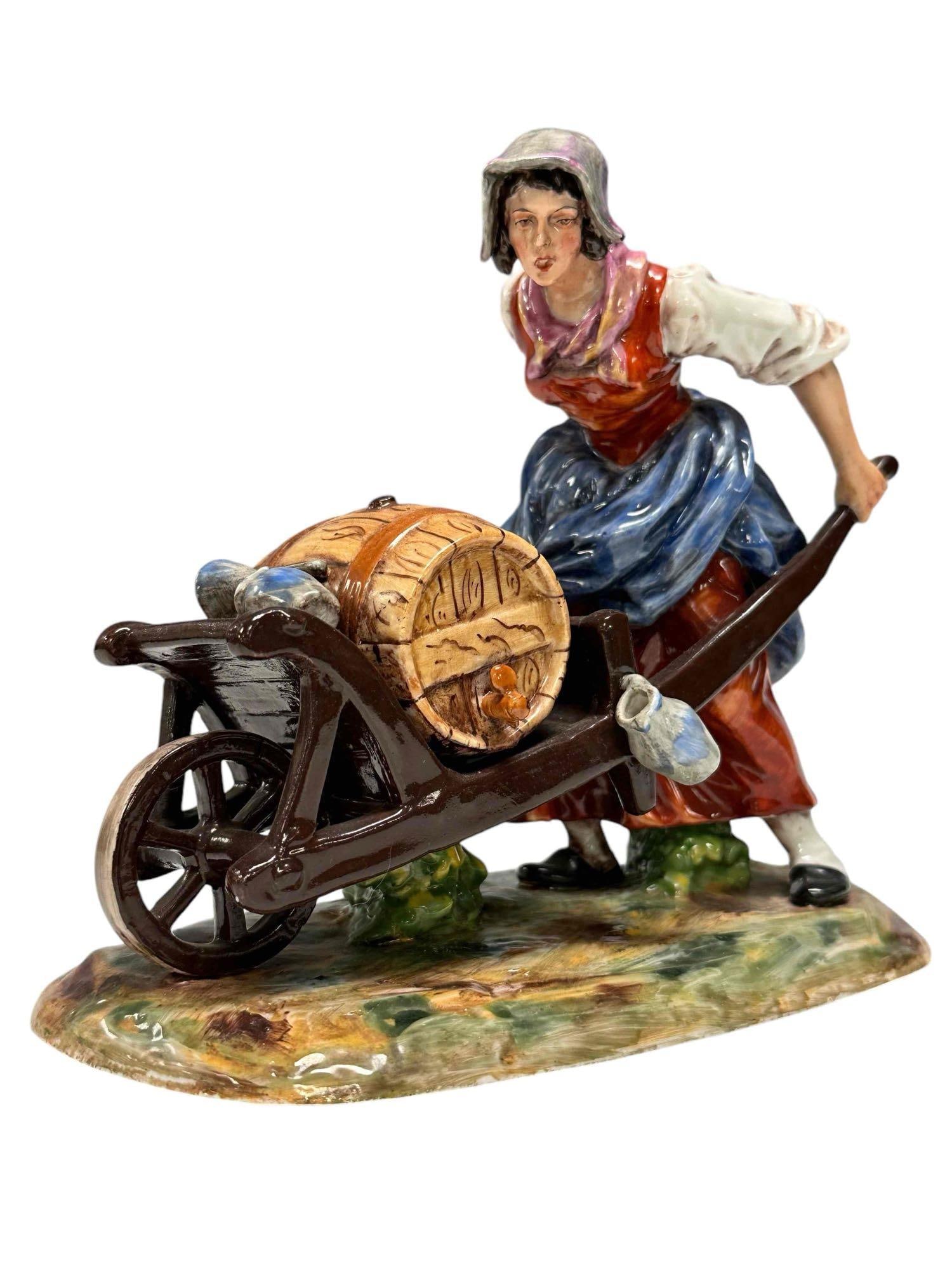 Italian / Dresden Figurine of Woman Working: Depicting a woman pushing a wheelbarrow with a Whiskey barrel and stoneware jugs. Stamped Dresden on bottom see photo. Measuring approx 7" tall x 8" wide. Very good no issues, see photos