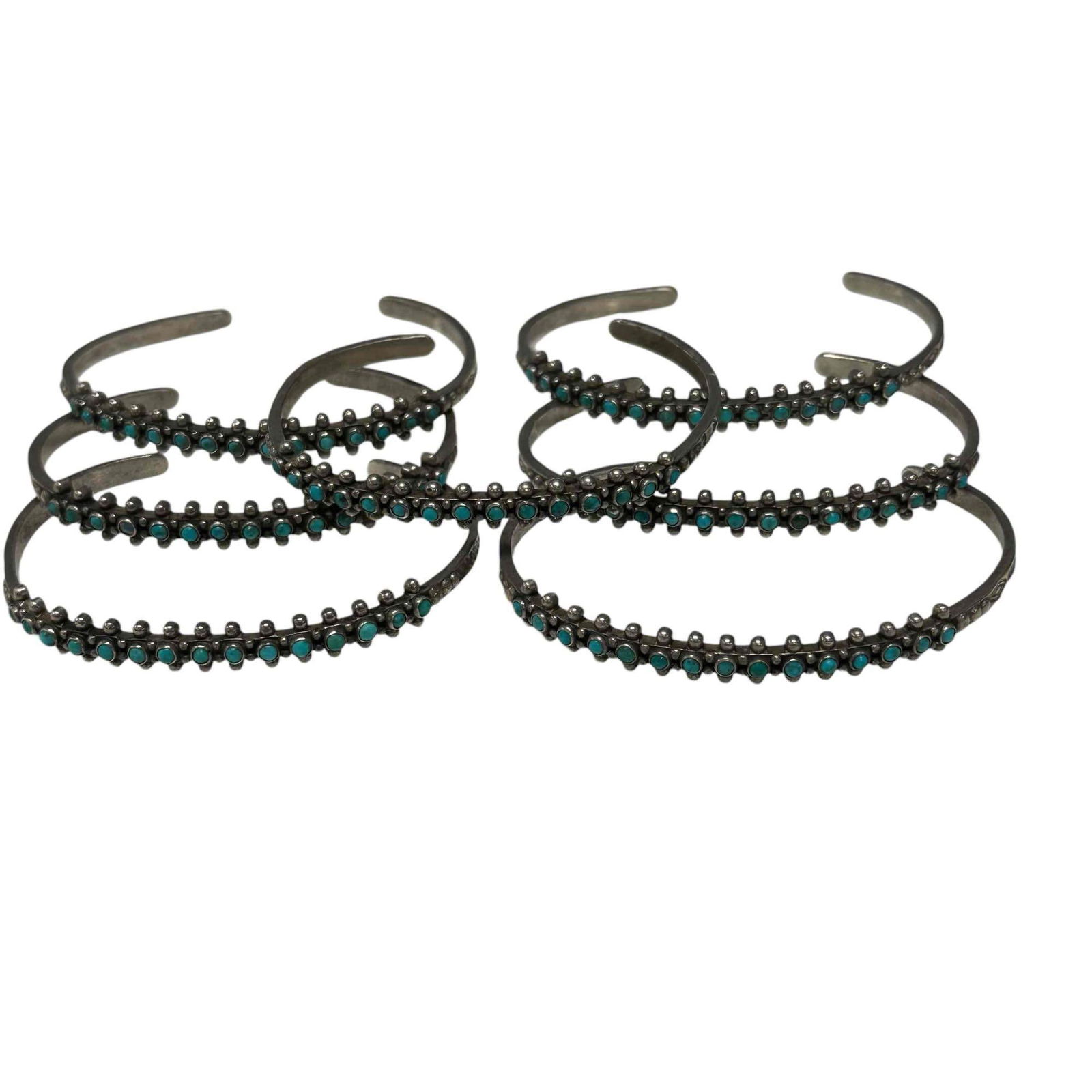 Zuni Seven Sterling Silver Turquoise Motif Cuff Bracelets: Seven Zuni sterling silver turquoise motif cuff bracelets. Condition: Missing stone on one of the bracelets. Stamp: No Markings. Gross Weight: 49.38 dwt.