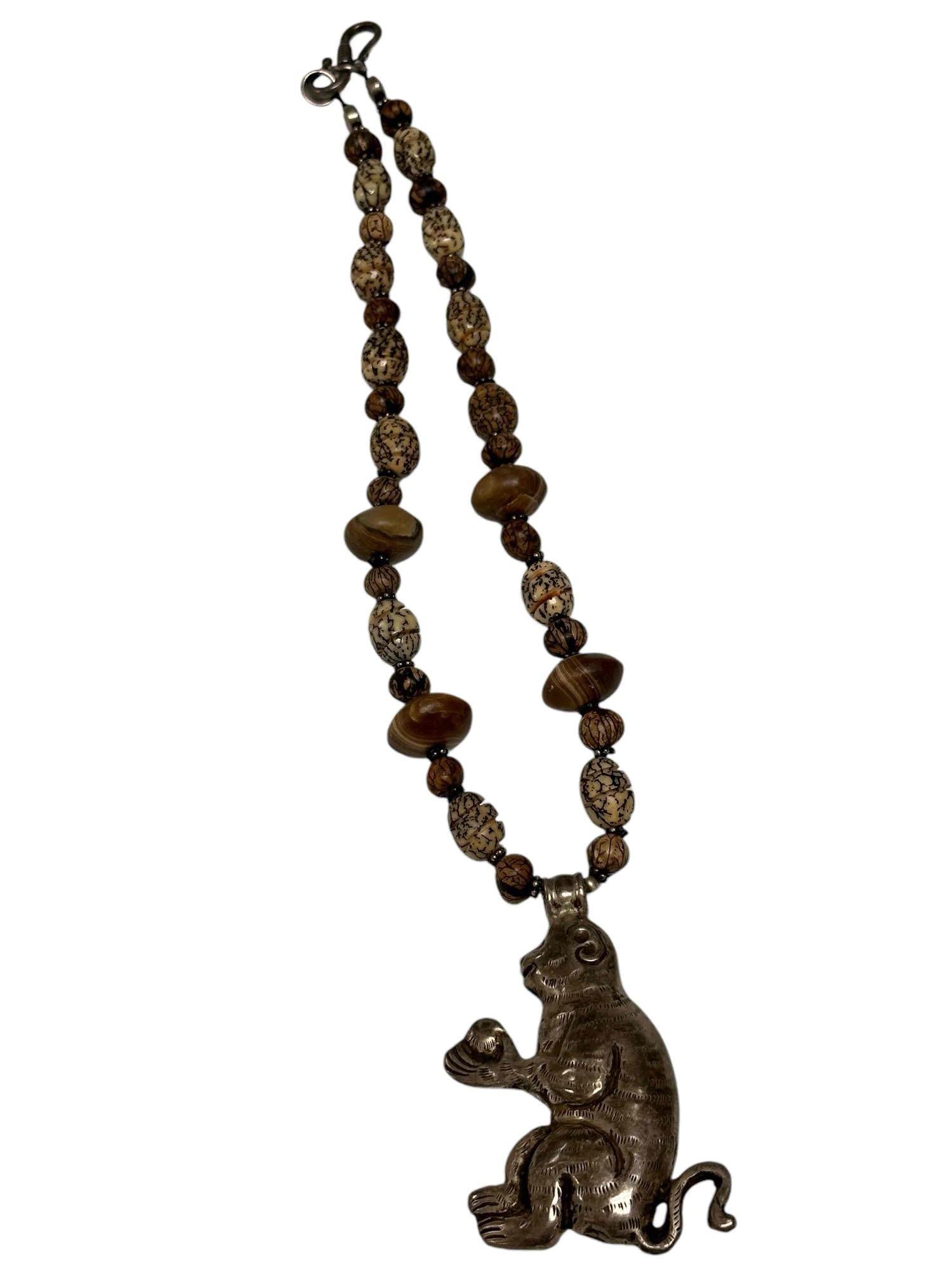 Agate and Wood Bead Pendant Monkey Necklace: Necklace is comprised with wood and agate beads and a sterling silver monkey motif pendant. Measures approx 19" long. Stamp: H. Gross Weight: 50.73dwt.