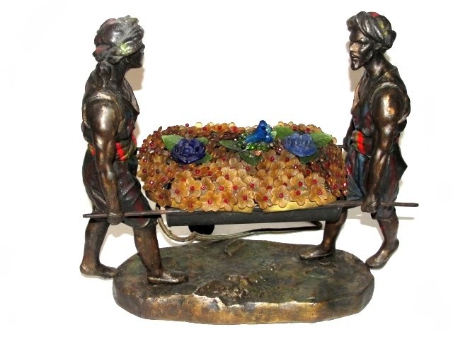 Arabian Lamp Two Figures Carrying Cache: Cold painted with beaded glass cover over light section. Condition light wear to metal, one glass bead missing otherwise good. Very interesting lamp. 12'' x 13'' x 5''. 4