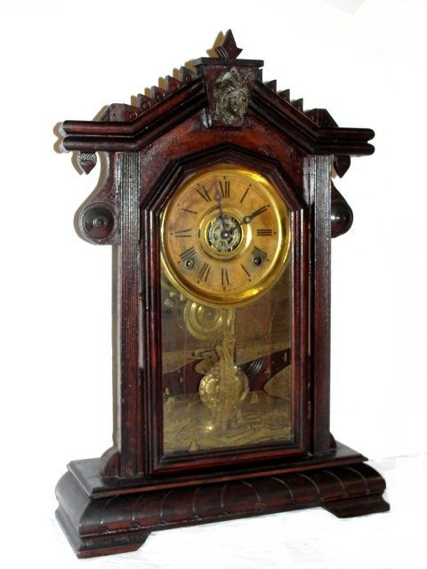 Victorian Walnut Carved Clock With Lady Head: Having a metal head of Victorian lady and Statue Of Liberty painted on door and alarm. Condition old tired finish, appears to work no key untested. Est. size 22 1/2'' x 14'' x 4'' '' ALL CLOCKS SOLD A