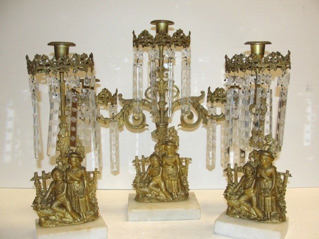 Figural Prism Girandole Garniture Set 1880's: Dore/ Brass one-triple two-single, depicting young boy and girl sitting by fence, Triple 17"H. 16'' W. Singles 14'' Tall, Condition very good, with all correct prisms on marble bases.