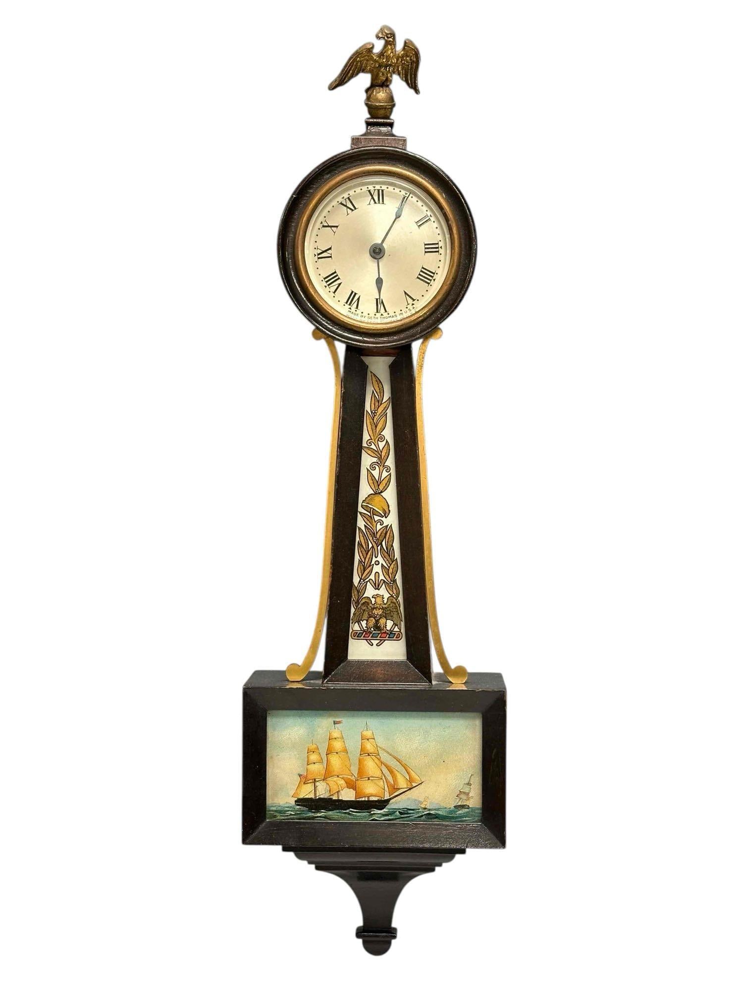 Seth Thomas Banjo Clock with Reverse Painted Clipper: Seth Thomas Ramsgate Banjo Clock with reverse painted clipper ship and eagle finial. Measuring approx. 21.5" tall. In good condition with top piece of trim missing above center body glass, see photos.