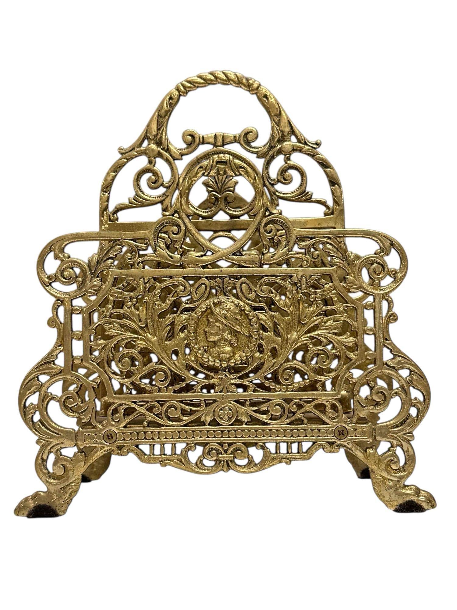 Art Nouveau Brass Paw Footed Magazine Rack: Ornate brass magazine rack art nouveau style with center woman medallion with scrollwork throughout on paw feet in Bradley & Hubbard manor. Measuring approx. 11.75" tall by 10" wide. In good condi