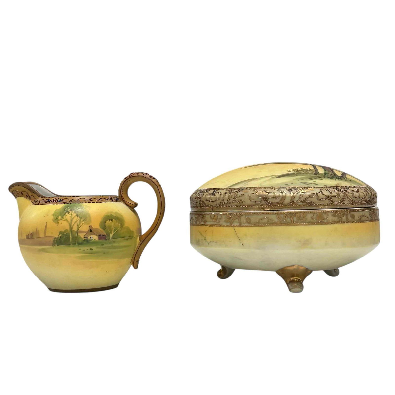 NIPPON Landscape Footed Trinket Box and Creamer: Nippon porcelain lidded trinket or powder box and creamer. Both in country landscape motif on yellow backdrop and enameled trim accent. Measuring approx. 3.25" to 3.5" tall. In good age appropriate co