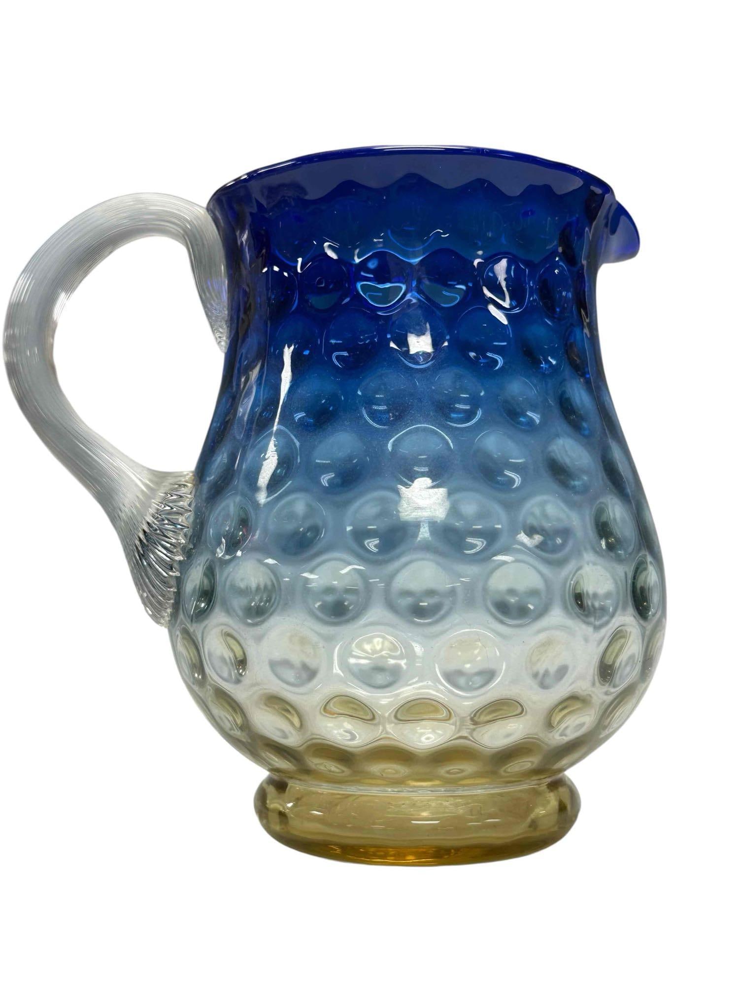 Victorian Era Bluerina Coin Dot Glass Pitcher: New England Glass Company Bluerina Inverted Thumbprint or Coin Dot pitcher. Having gradient shading from deep cobalt blue rim to honey amber base and reeded handle. Measuring 7" tall. In good conditio