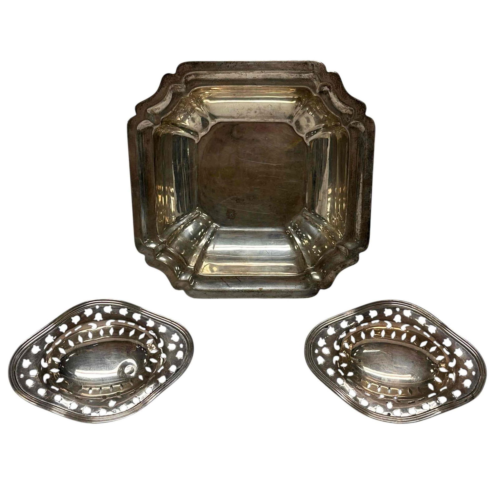 Three Sterling Silver Nut Dishes 188 Grams: Includes two Wallace pierced footed nut dishes 3.75" long by 2.5" wide on four ball feet and square scalloped "Windsor" nut bowl. Measuring approx. 5.5" wide by 1.25" tall and weighting 188 grams tota