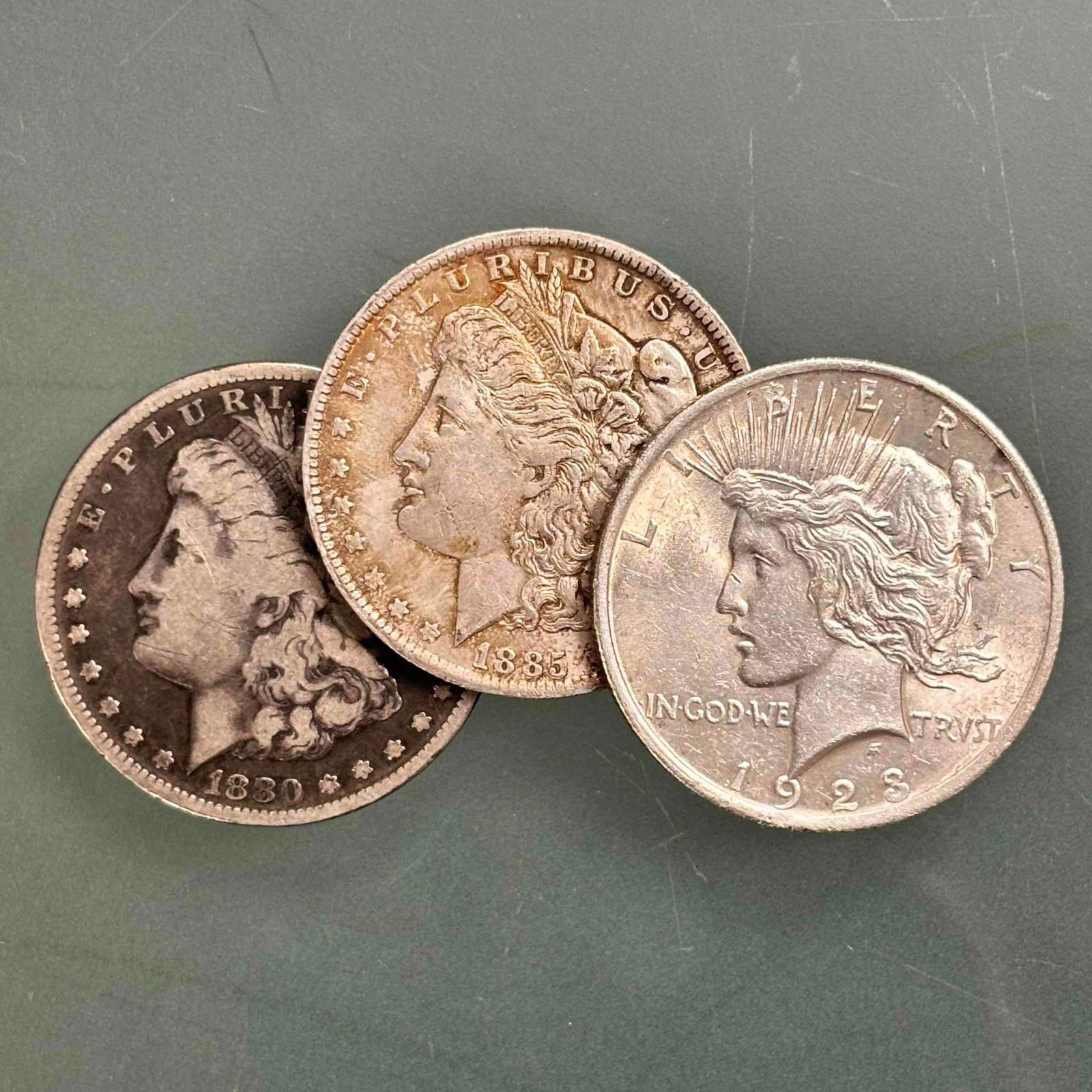 Morgan & Peace Silver Dollars 90% Silver (3): Late 19th early 20th century 90% silver including; 1880 Morgan silver dollars, 1885 Morgan silver dollar and 1923 Peace silver dollar. In age appropriate condition, see photos.