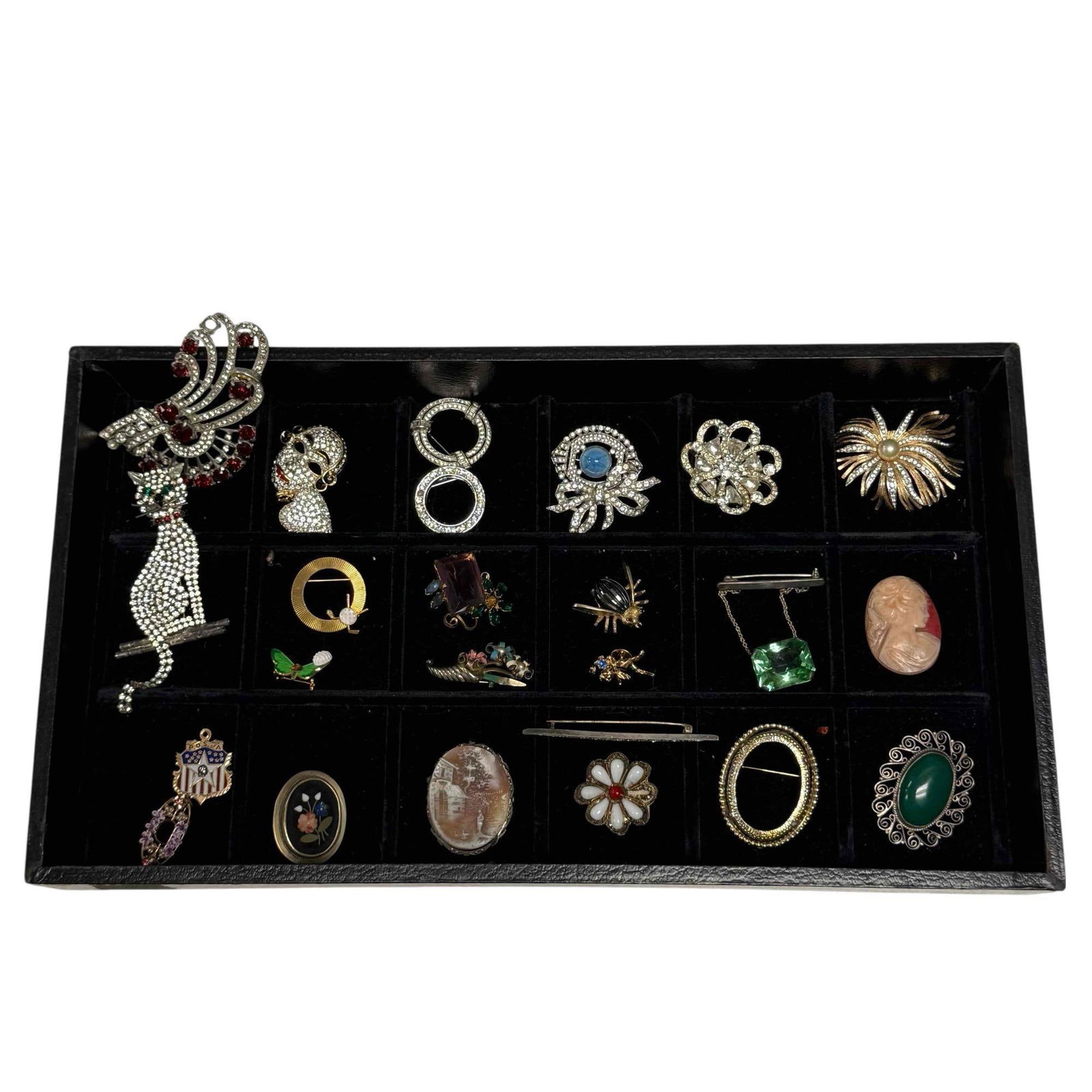 26 Brooches / Pins -Rhinestones, Ugo Correani Cameos etc.: Including a Ugo Correani masquerade rhinestone mask, Trifari, Krussman and Fishel blue opal with rhinestones, Trifari ribbon rhinestone brooch, PENNETA pins with rhinestones, larger rhinestone seated