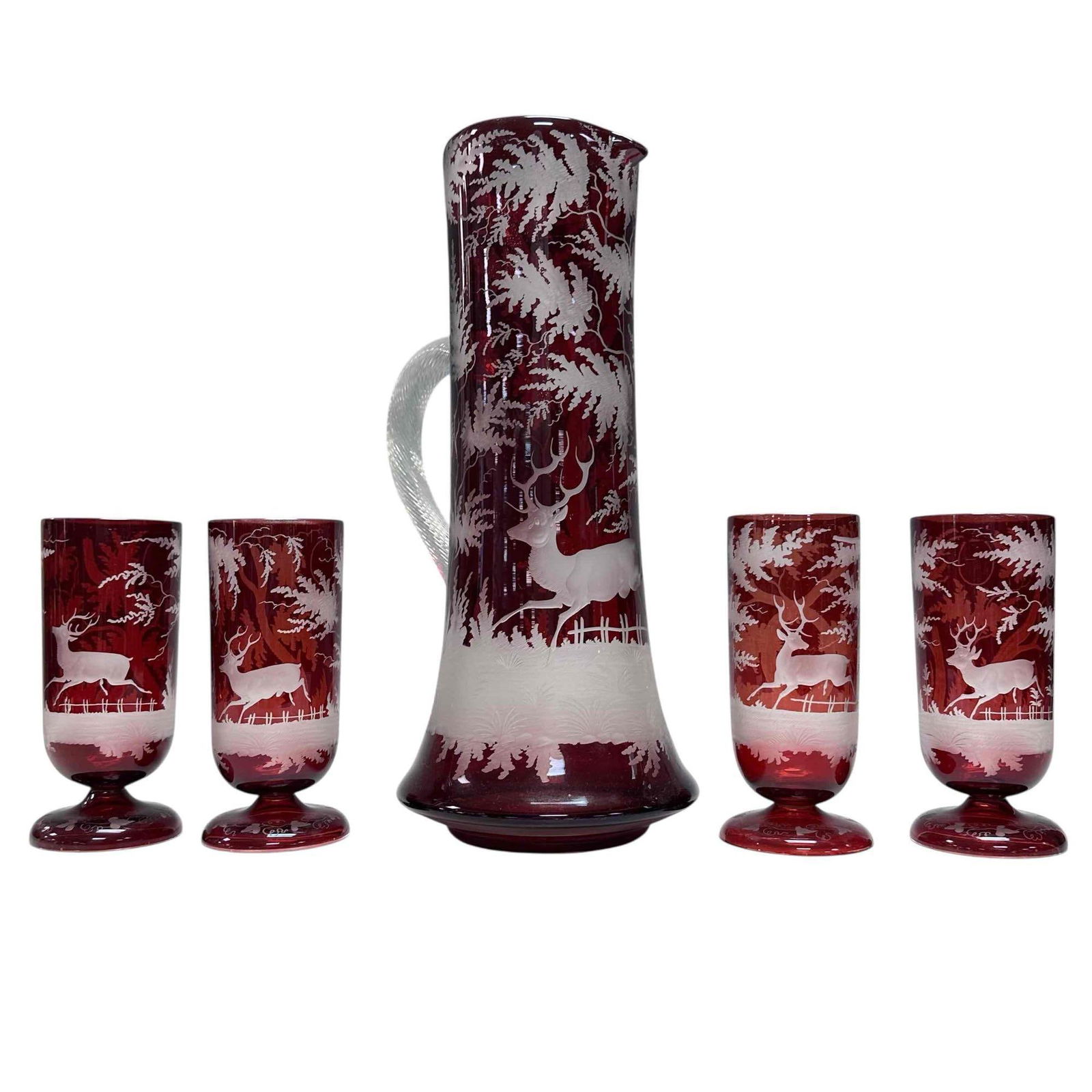 Stag Ruby Etched to Clear Bohemian Glass Pitcher & Glass Set (5): Ruby etched to clear/frost Bohemian pitcher and glass drinking set for four. Depicting forest and stag motif with applied clear twisted handle with four pedestal glasses. Pitcher measuring approx.