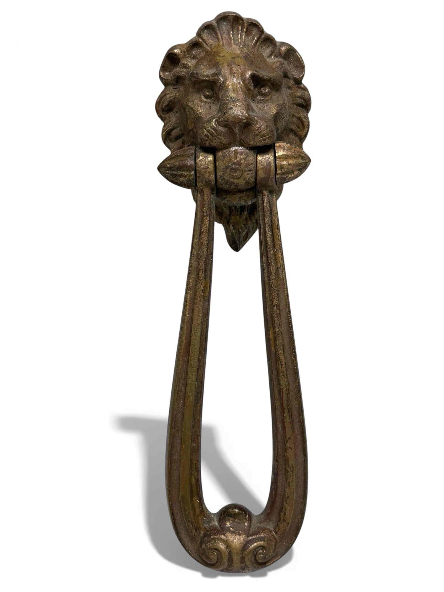 Elongated Lions Head Door Knocker: Great lion's head heavy-duty door. Knocker runs through the lion's mouth as if he is biting on a b, one holding the long knocker handle. Age-appropriate condition. Measures 9" Long by 2.5" wide and st
