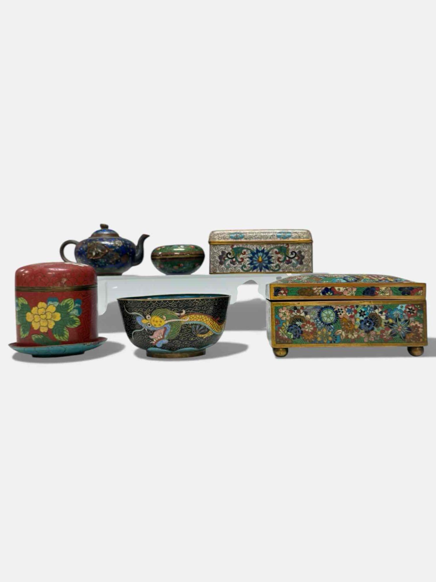 Cloisonne Enameled Lidded Boxes Teapot and Dishes (7): Cloisonne pieces Includes; enameled jewelry box with blue floral and scroll pattern on white background 2" tall by 4.75" wide by 3" deep, elaborate Millennium Flowers footed chest with wood lined inte