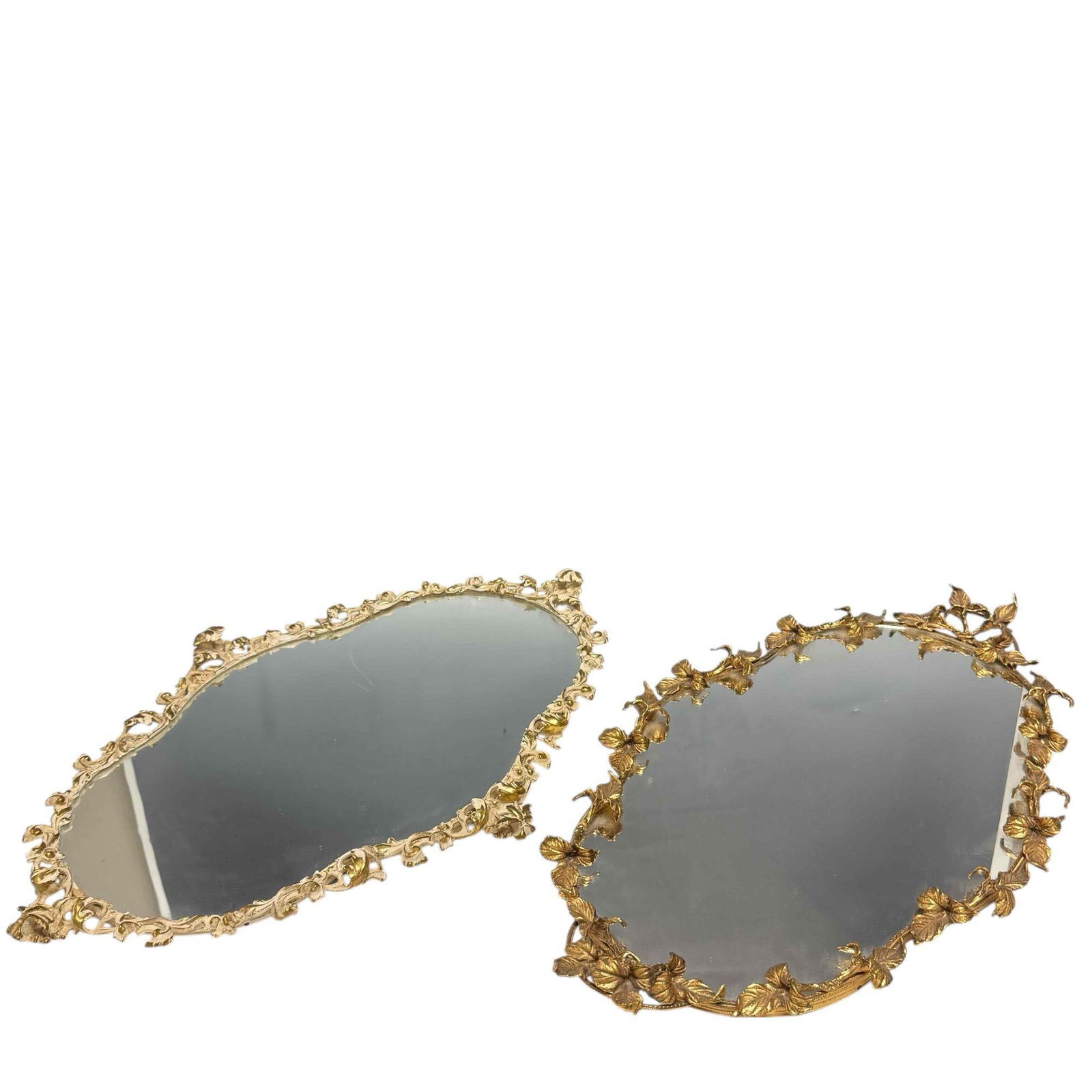 Two (2) GLOBE 24k Gold Plated Ornate Vanity Mirrors: Two shapely and ornate 24 karat gold plated metal vanity powder room trays with mirrored surfaces. Measuring approx 26" l x 17" w x 2" h. Mid 20th century trays in good condition, light use and wear a