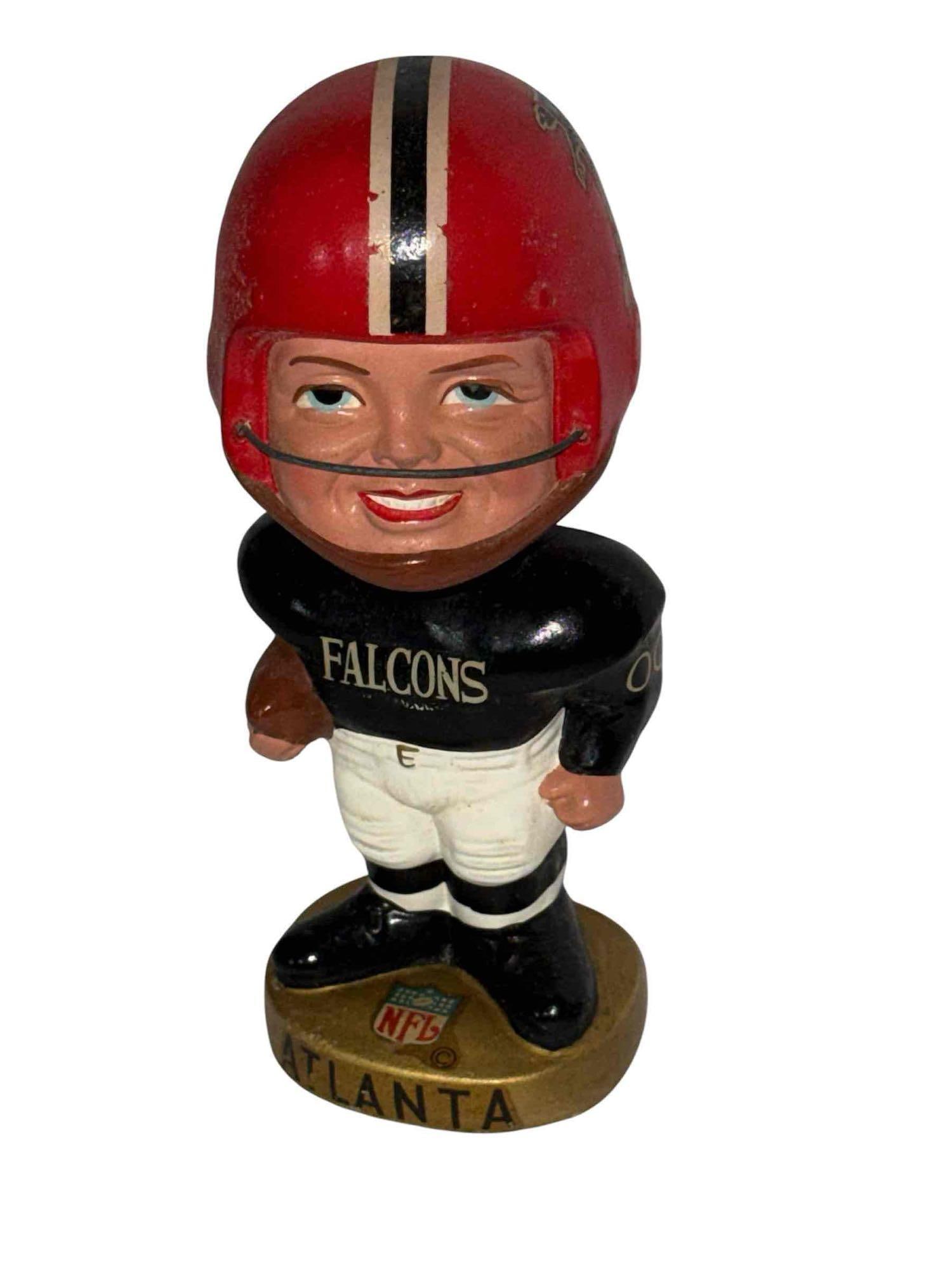 1968 Atlanta Falcons Realistic Face Gold Base Bobblehead: Version that features a more "realistic" face with a different smile and eyes smaller and looking up. These are not as common. Overall very nice condition with some signs of age and handling. Decal on
