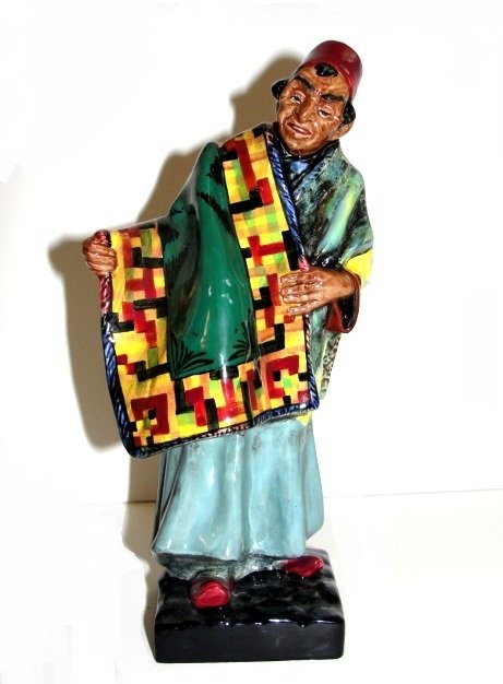 Royal Doulton Figurine Carpet Seller HN 1464: This romantic piece summons up the charms of Middle Eastern cultureâ€”famed for its beautiful carpets. Designed by Leslie Harradine, this figurine stands approximately 9â€ tall. The seller lea