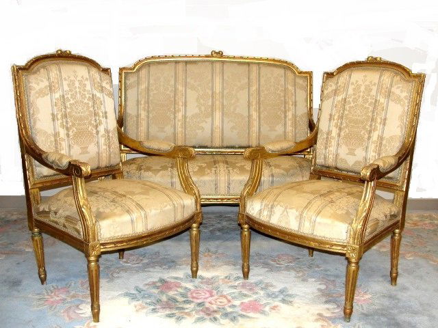French Louis XVI Three Piece Gilded Parlor Suite: Ca. 1875 = 1900 Settee and two arm chairs. Condition overall good, frames with loose glue joints, minor loss of gilt, one leg with old repair and fabric with light wear and one stain area. Still looks