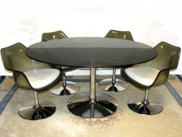 Sarrinen Style Mid Century Modern Dining Set: Vintage mid century modern dining table with four acrylic/plastic arm chairs having a chrome tulip shaped base in the Saarinen style and oval smoked glass top. This vintage matching all original set h