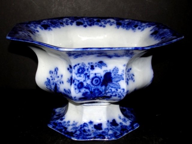 Flow Blue Footed Compote Center Bowl: Eight sided bowl with flared rim and oriental floral designs. Condition overall very good, tight crows foot hair crack on inside, does not show on outside of bowl. 6 1/4'' x 9 3/4''. The diamond-shape
