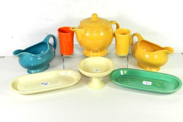Collection of Vintage Fiesta Serving Pieces: Including 2 sauce boats: 1 in yellow, 1 in light blue. Light blue has a chip on the bottom. Two juice glasses: 1 yellow, 1 orange. Two utility trays: 1 ivory, 1 light green. Ivory sweets comport-has a