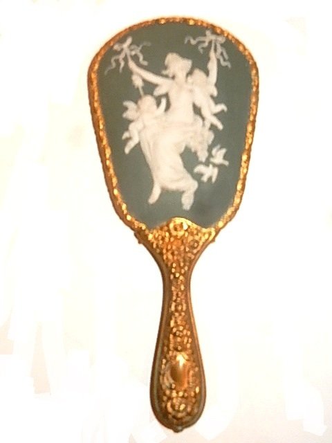 Repousse Wedgwood /Jasperware Mirror: Fine ladies polished brass / gold tone repousse mirror frame with Wedgwood / jasperware plaque of figure on swing adorned by winged cupids and love doves with beveled mirror. Condition very good. L. 9
