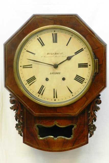 Birkle Bros. & Co. Wall Clock: Birkle Bros. & Co. wall clock, London. Octagonal face with painted steel dial and light floral molding dÃ©cor. Lower section veneer cracked across the middle near glass pendulum window. Clock in wor