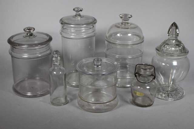 7 Country Store Lidded Apothecary Glass Jars: Late 19th century through early 20th century glass jar collection. Tallest is approx. 12" in size. Country store various jar.