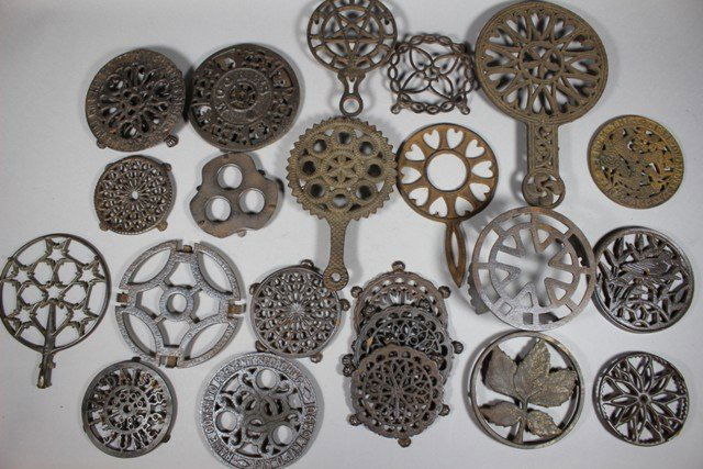Group of 25 Cast Iron Trivets: Group from late 19th century through the early 20th century. Including ornate handled trivets as well as traditional embossed designs as shown. Various NY, Chicago, Ohio and others. Normal use and wea