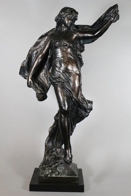 After Eugene Marioton Classical Maiden: Large heavy bronze patinated plaster sculpture depicting a classical maiden in flowing drapery on wooden stand, signed "Eug. Marioton." H. 31". Half inch chip on left hand. 1983. Some other damage and
