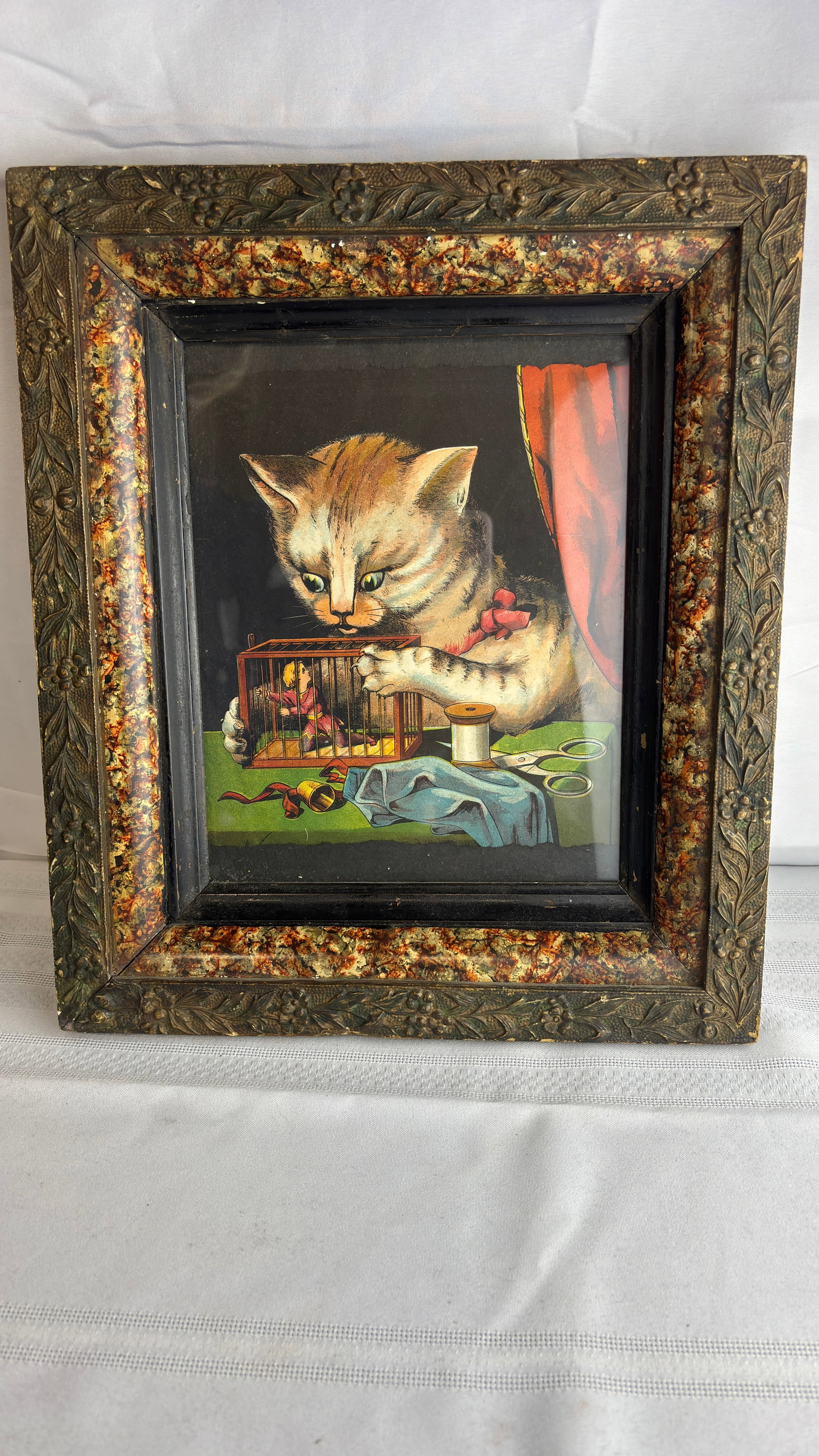 Antique Wide-Eyed Cat Looking Curiously into Cage with Miniature Person Inside Litho/Print: Antique Wide-Eyed Cat Looking Curiously into Cage with Miniature Person Inside Litho/Print of some type.