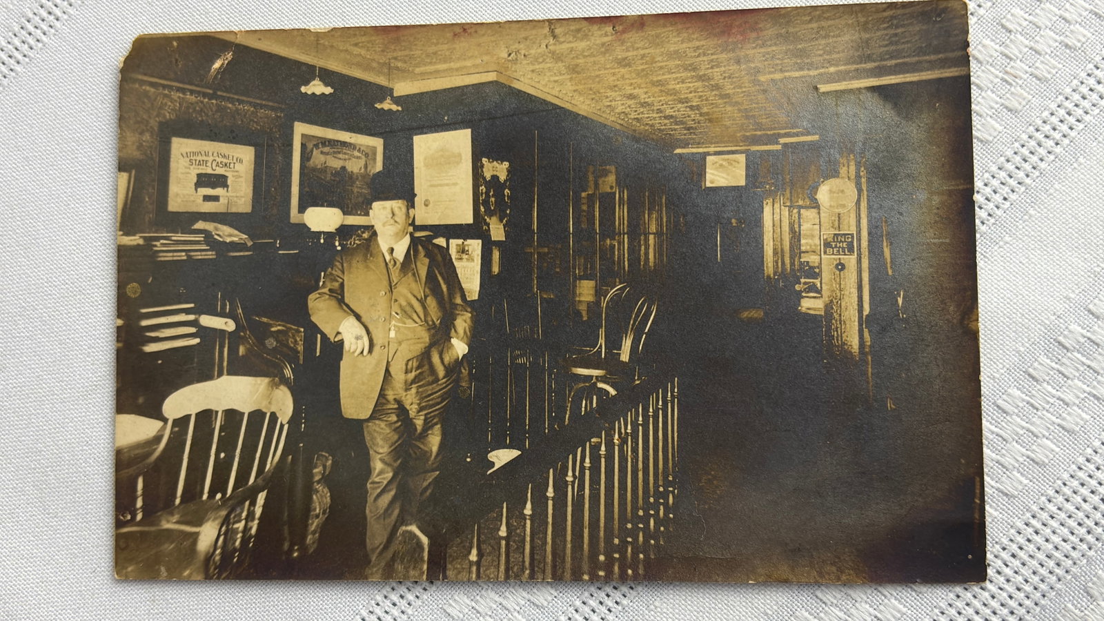 Antique New England Collectible Real Photo Post Card, RPPC, Possibly Taunton Mass. Area: Antique Taunton, Massachusetts Post Card, scene of a gentleman in possibly a funeral home. He stands next to advertisements of casket companies. In good overall condition with a small tear at corner, 