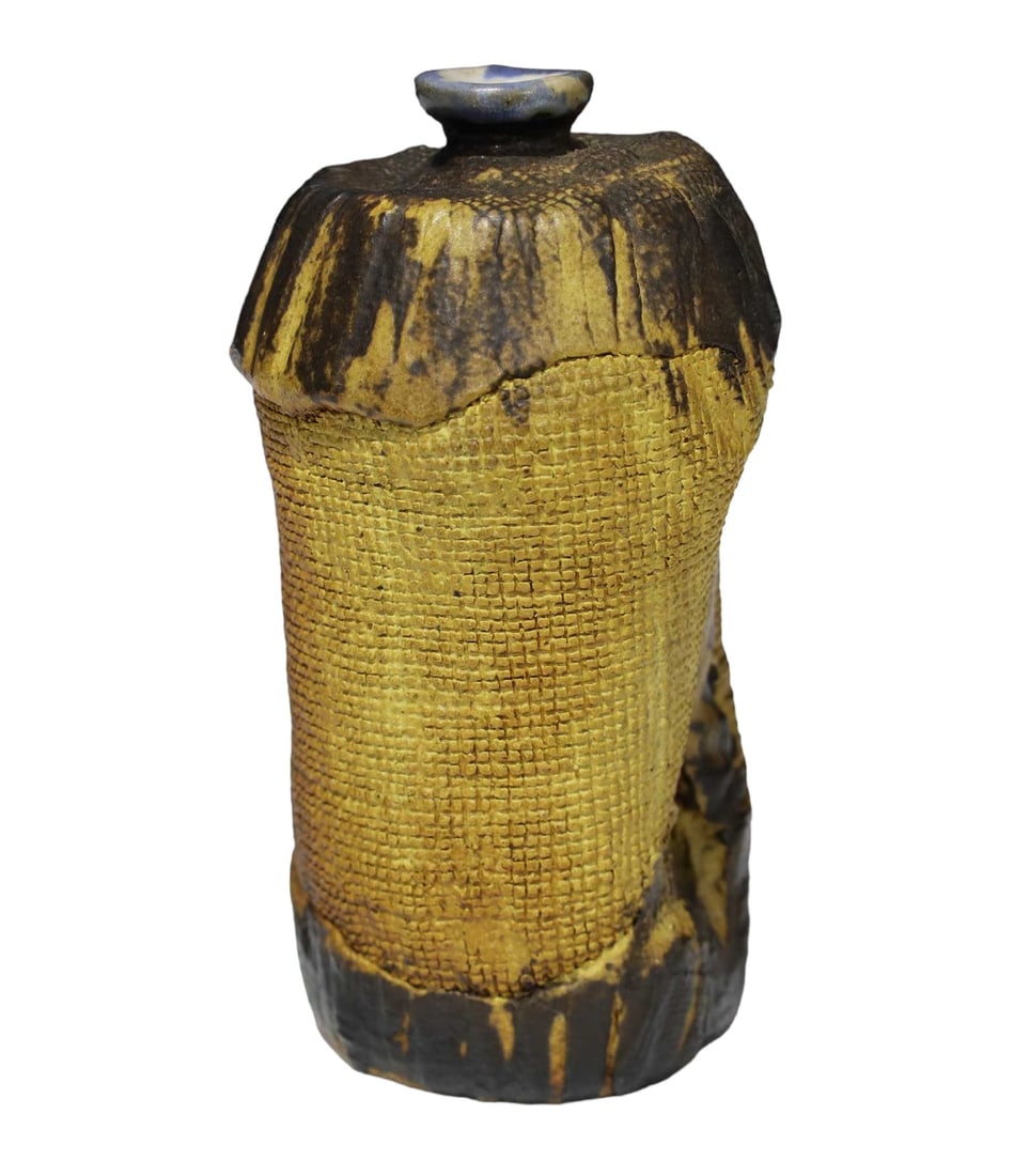 Organic Ceramic Vase: This artfully crafted vase features Modernist style matte glazes in tan and brown, accented with a striking blue at the lip. The free form bottle design, enhanced by its fabric texture, makes it a uni