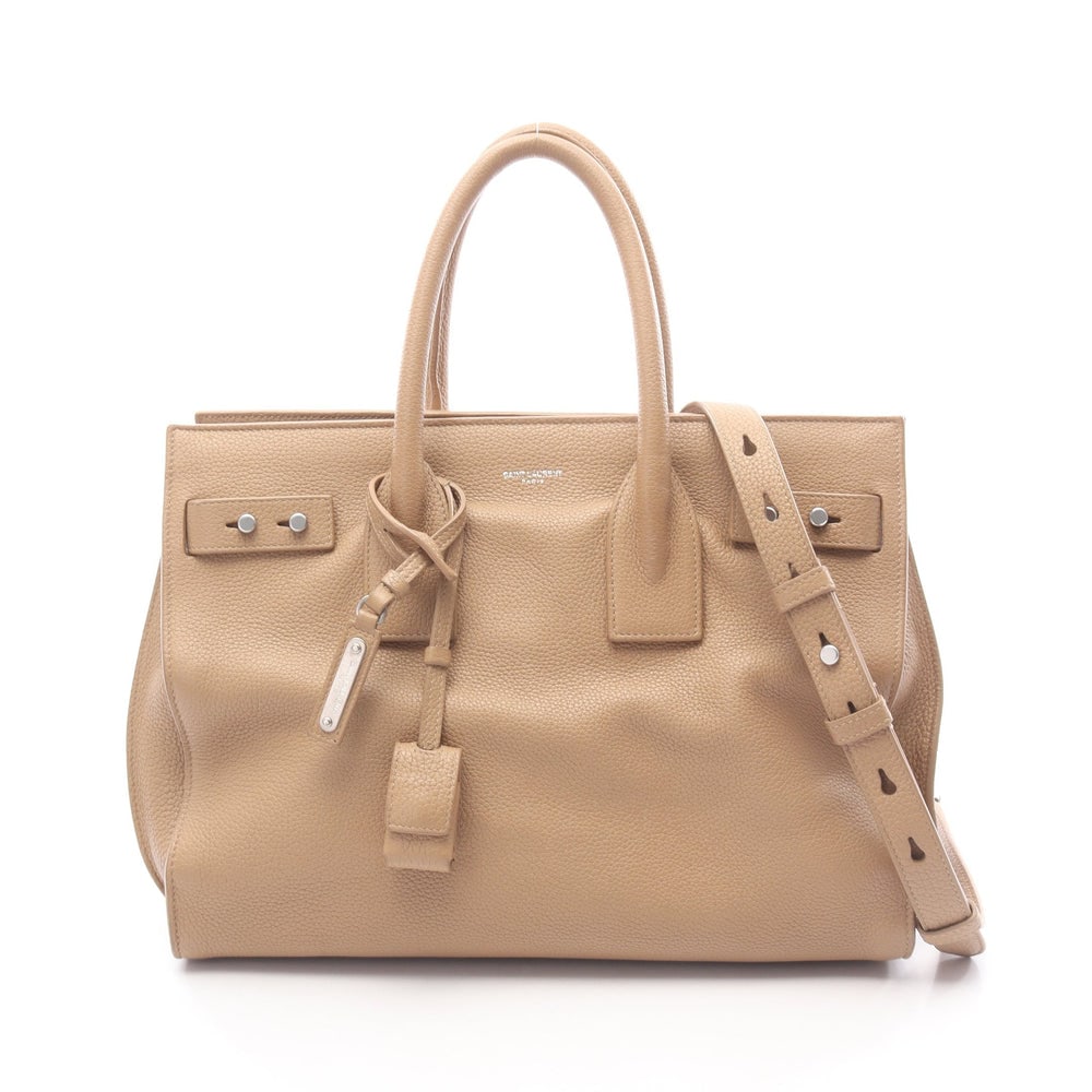 Saint Laurent Sac De Jour Beige: Sac De Jour Souple 2 way tote in beige leather. Includes shoulder strap, crochet, padlock, and two keys. Size 32 x 25 x 15 cm.