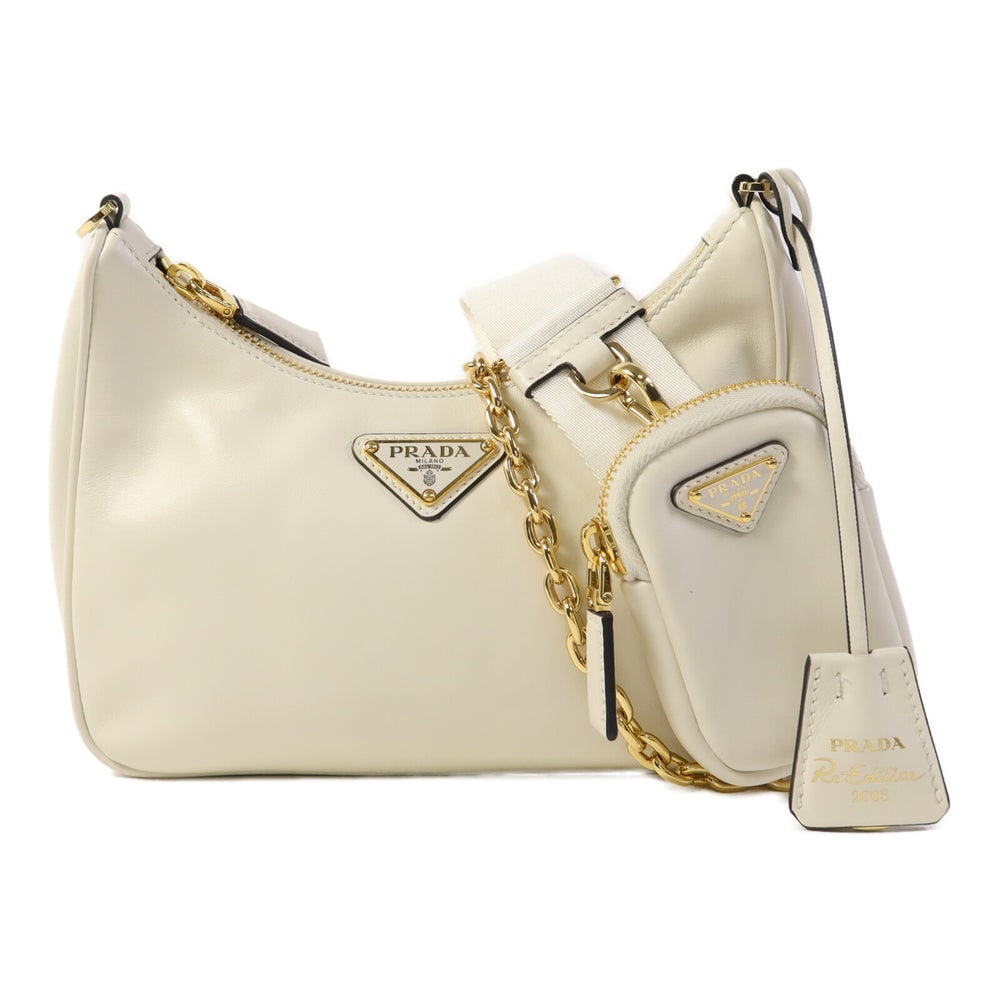 Prada Re-Edition 2005 White: White and cream calfskin Prada Re-Edition 2005 2-way shoulder bag with shoulder strap, clochette, and pouch. Approx. 22 x 12-16 x 6 cm; strap 80-108 cm. Authentic and authenticated.