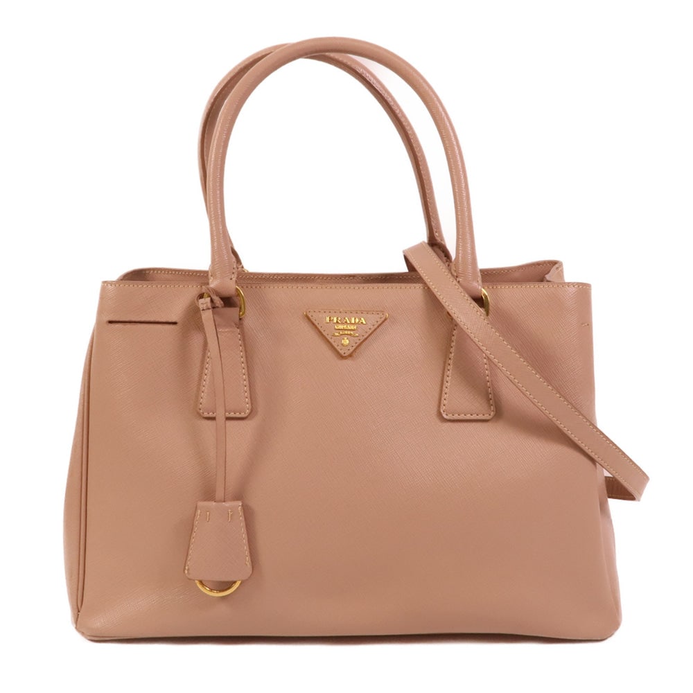 Prada Galleria 2 Way Beige: Galleria 2 way shoulder bag in beige saffiano leather. Includes guarantee, shoulder strap, and clochette. Size 32 x 21 x 14 cm.