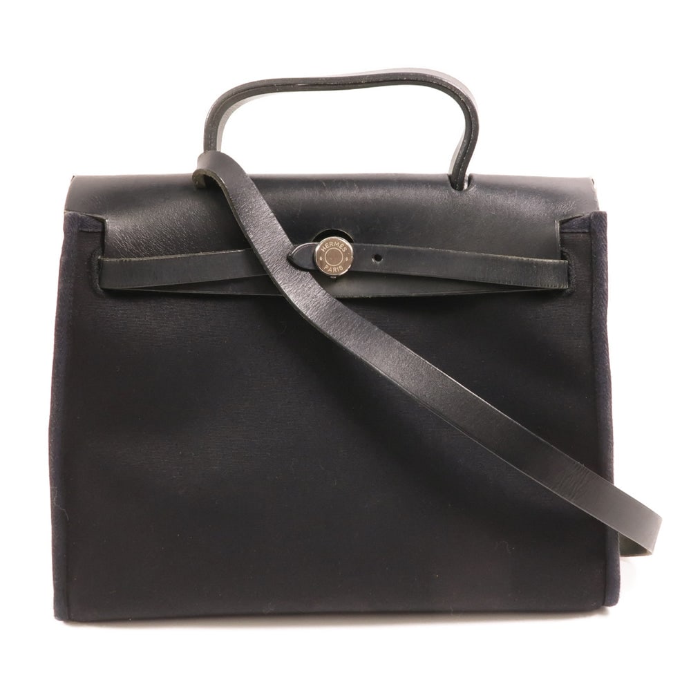 Hermes Herbag 31 Noir: Black canvas Hermes Herbag 31 2-way shoulder bag with storage bags, clochette, key, and cadena. Approx. 29 x 27 x 12 cm; handle 22 cm; strap 98 cm. 2003 year stamp. Authentic and authenticated.