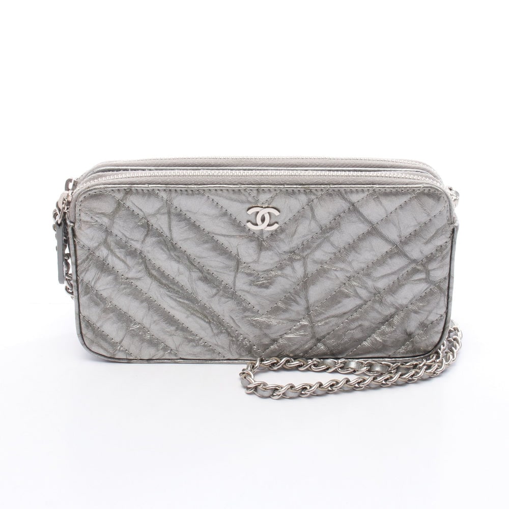 Chanel Chevron V-Stitch WOC Silver: Silver leather Chanel Chevron V-stitch chain wallet with guarantee card and serial seal. Approx. 18 x 9 x 3 cm; strap 132 cm. Model A82527. Authentic and authenticated.