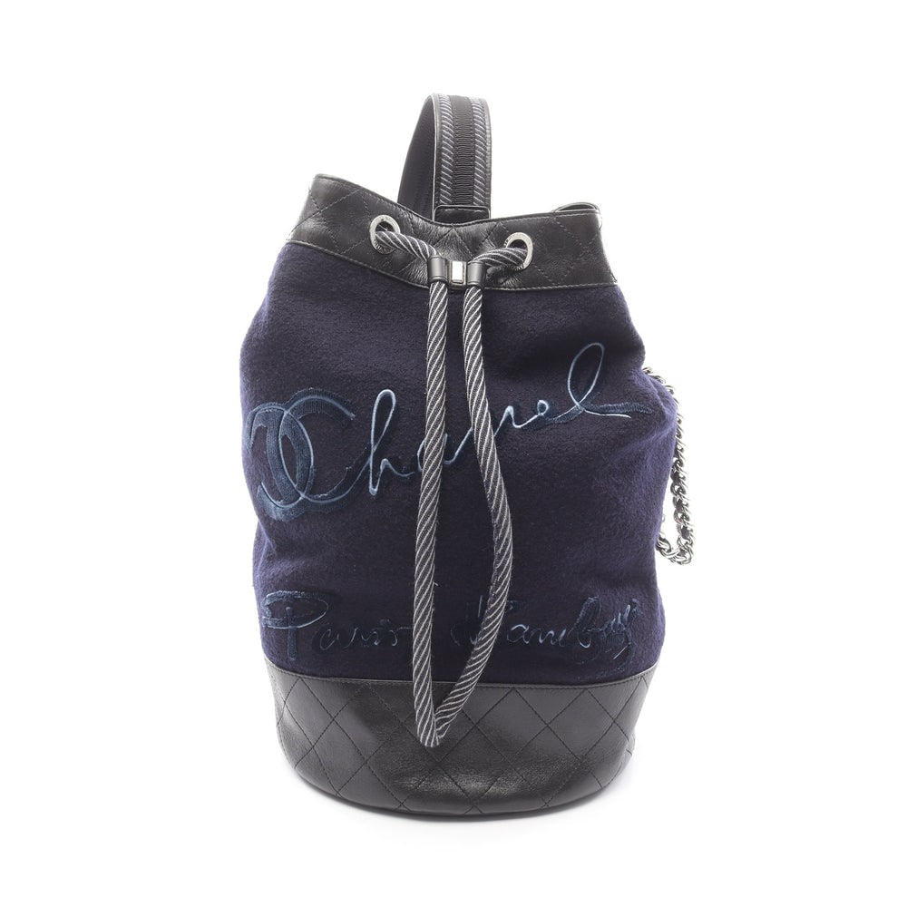 Chanel Drawstring Shoulder Navy Black: Navy and black wool and leather Chanel embroidery drawstring shoulder bag with silver hardware and serial seal. Approx. 24 x 41 x 24 cm; strap 81 cm. Model A57519. Authentic and authenticated.