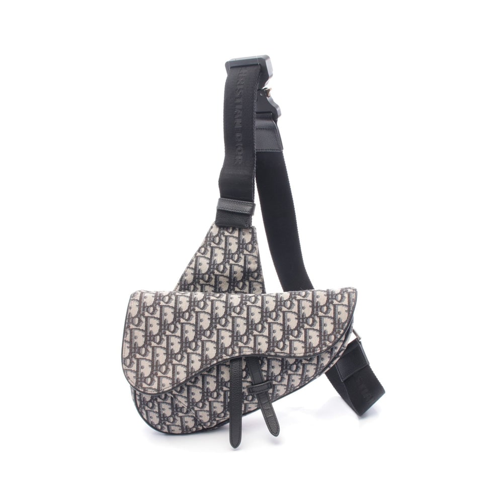 Dior Saddle Oblique Body Bag Beige: Beige, black, and blue canvas and leather Saddle Oblique jacquard body bag. Approx. 26 x 18.5 x 3 cm; max strap 115 cm. Model 1ADPO093YKY. Authentic and authenticated.