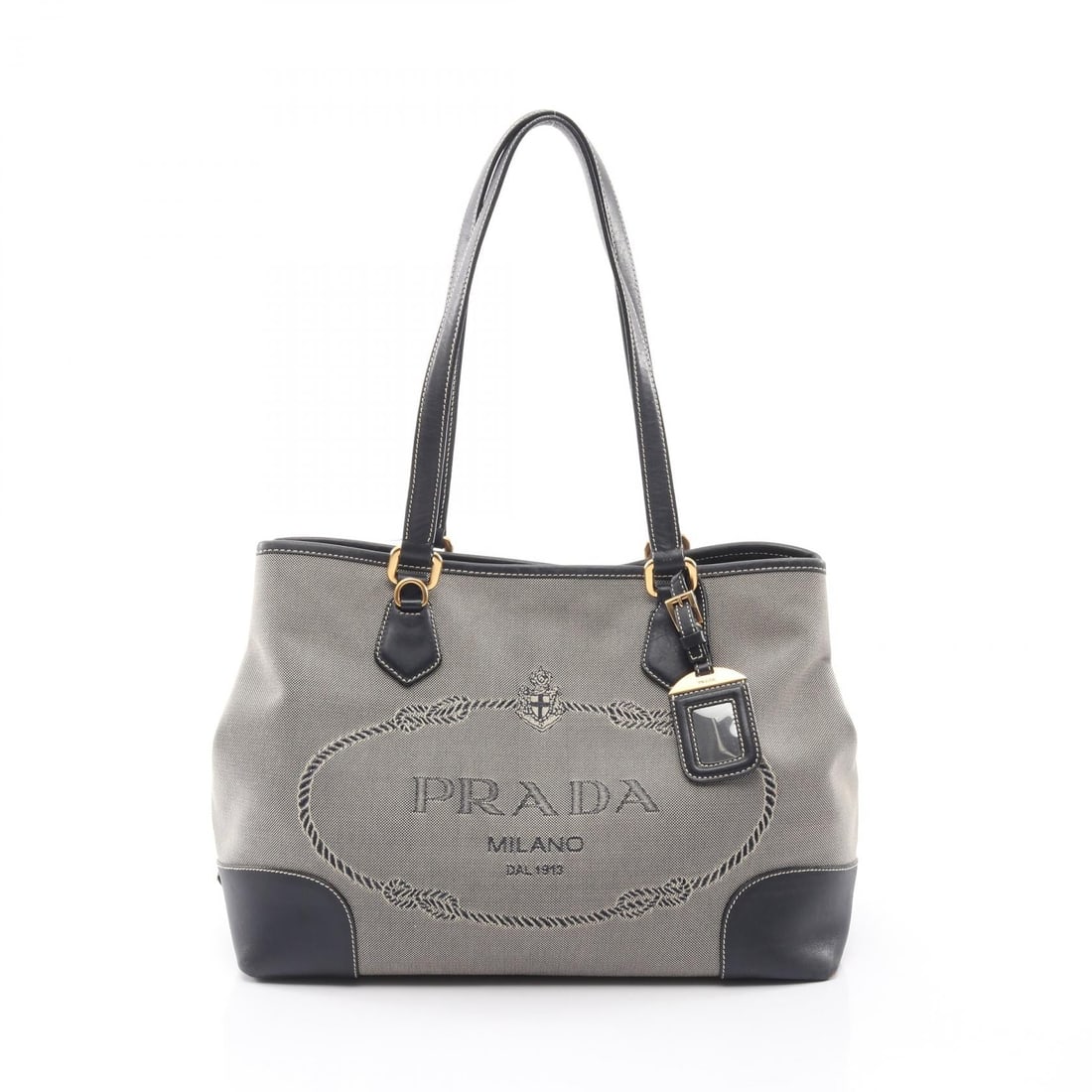 Prada Logo Jacquard Tote Beige Navy: Authentic and authenticated Prada logo jacquard tote shoulder bag in beige/navy canvas and leather. Approx. 25H x 33.5/34W x 14D cm with 56 cm strap and 24.5 cm max drop. Includes name tag.