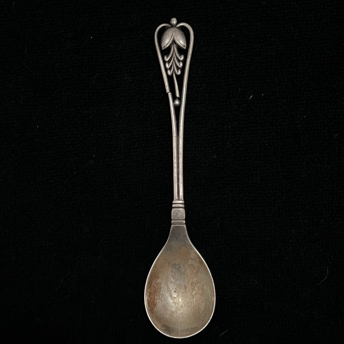 Georg Jensen 150 Sterling Silver Spoon 35.8 g: Sterling silver spoon with elongated bowl and openwork floral finial handle. Marked "150," dotted "GI" maker's mark, and "925.S" on the reverse, with additional struck marks on the bowl edge.