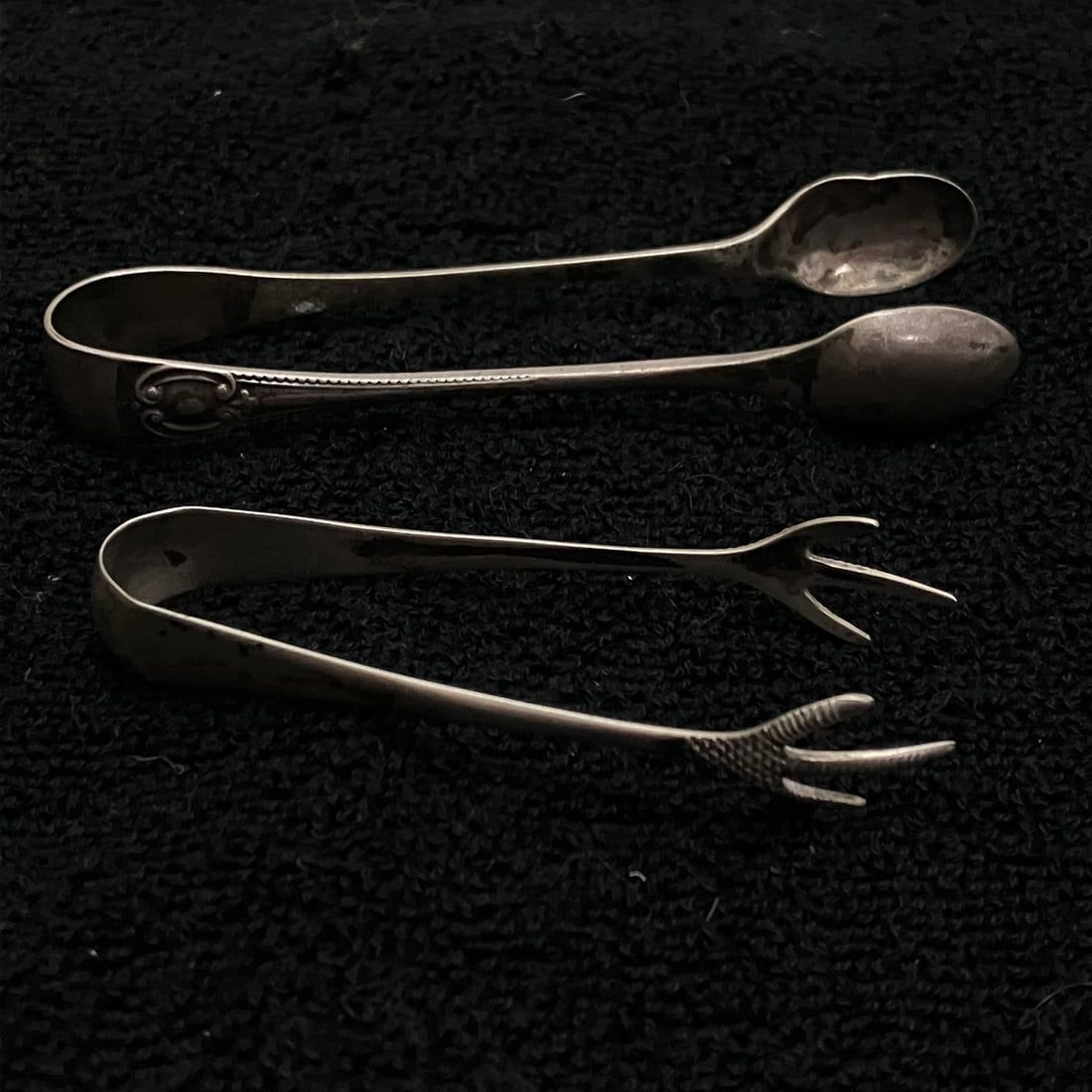 British Sterling Silver Sugar Tongs Pair 29.7 g: Pair of small hallmarked silver tongs comprising one spoon-end tong and one claw-end tong. Both pieces show British-style assay marks and partially legible maker’s marks. Combined weight shown is