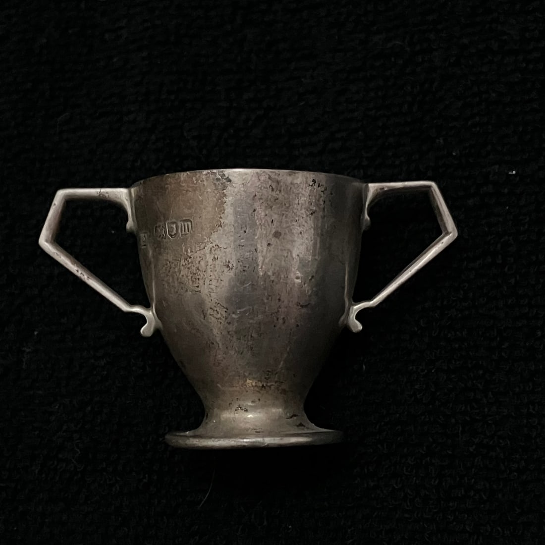Miniature Sterling Silver Two-Handled Cup 26.0 g: Small two-handled pedestal-form silver cup with angular handles and British-style hallmarks on the body. Base stamped approximately “FINNICANS REGD 368457.” Ruler image suggests an