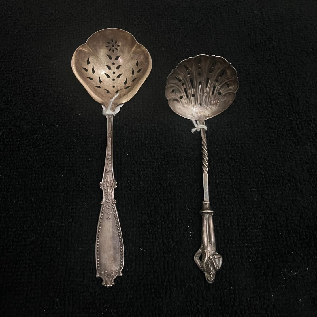 2 Sterling Silver Tea Strainers Spoons 38.7 g: Lot of two pierced sterling silver tea strainers. One is a Wallace example with an ornate flat handle and lobed pierced bowl; the second has a shell-form pierced bowl, twisted stem, figural terminal,