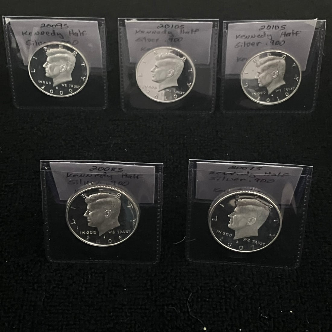 5 - Kennedy .90 Silver Half Dollar Cameo Proof: Lot of five Kennedy half dollar coins in individual plastic holders. Dates visible are 2007-S, 2008-S, 2009-S, and 2 of 2010-S. Coins show mirror-like proof surfaces in the provided images.